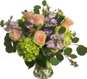 Opulent bouquet of purple, blush and green fresh cut flowers designed to impress in a tall clear glass vessel!