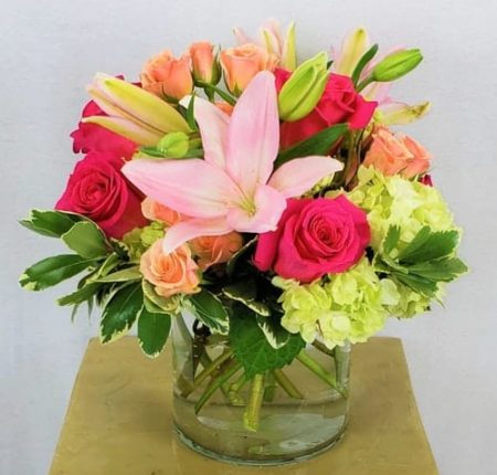 A classic low cylinder with stems of soft green hydrangea, soft pinks and hot pinks.