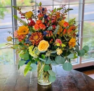 A stunning display of premium fall blossoms are are sure to make an impressive statement. This arrangement features, roses, sunflowers, snapdragons, bells of Ireland and many other flowers abundant in the autumn season.