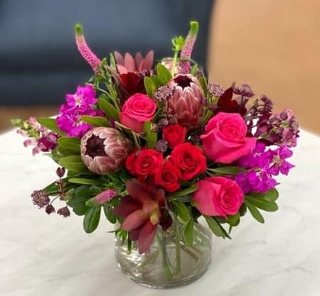 Warm up a crisp fall day with this combination of berry colored blooms. This arrangement features flowers in shades of red, hot pink and burgundy.
