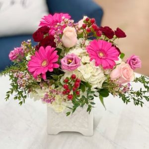 blooms in a romantic color palette of red, pink and white. This floral arrangement is designed in a ceramic lattice box.